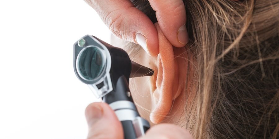 Closeup of examining ear with an otoscope